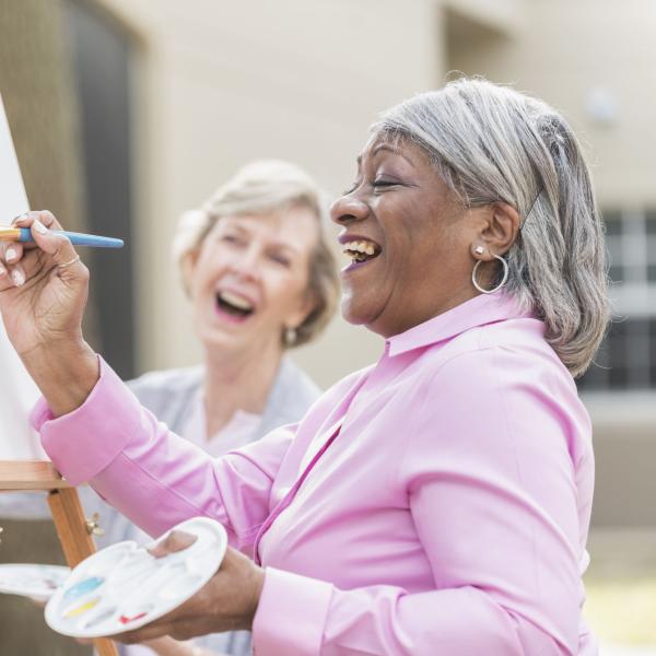 senior ladies laughing while painting on canvas