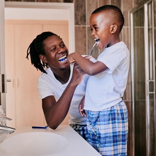 Young man and his son brushing their teeth in the bathroom at home