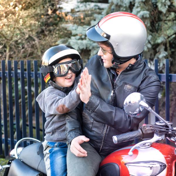 Dad and son are sitting on a motorcycle giving each other a high five