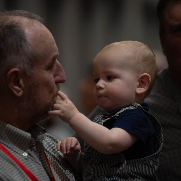 An older man holding a baby while the baby touches his face at the 2023 MFB State Annual Meeting.