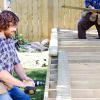 Two men building a deck in the back yard of a home.